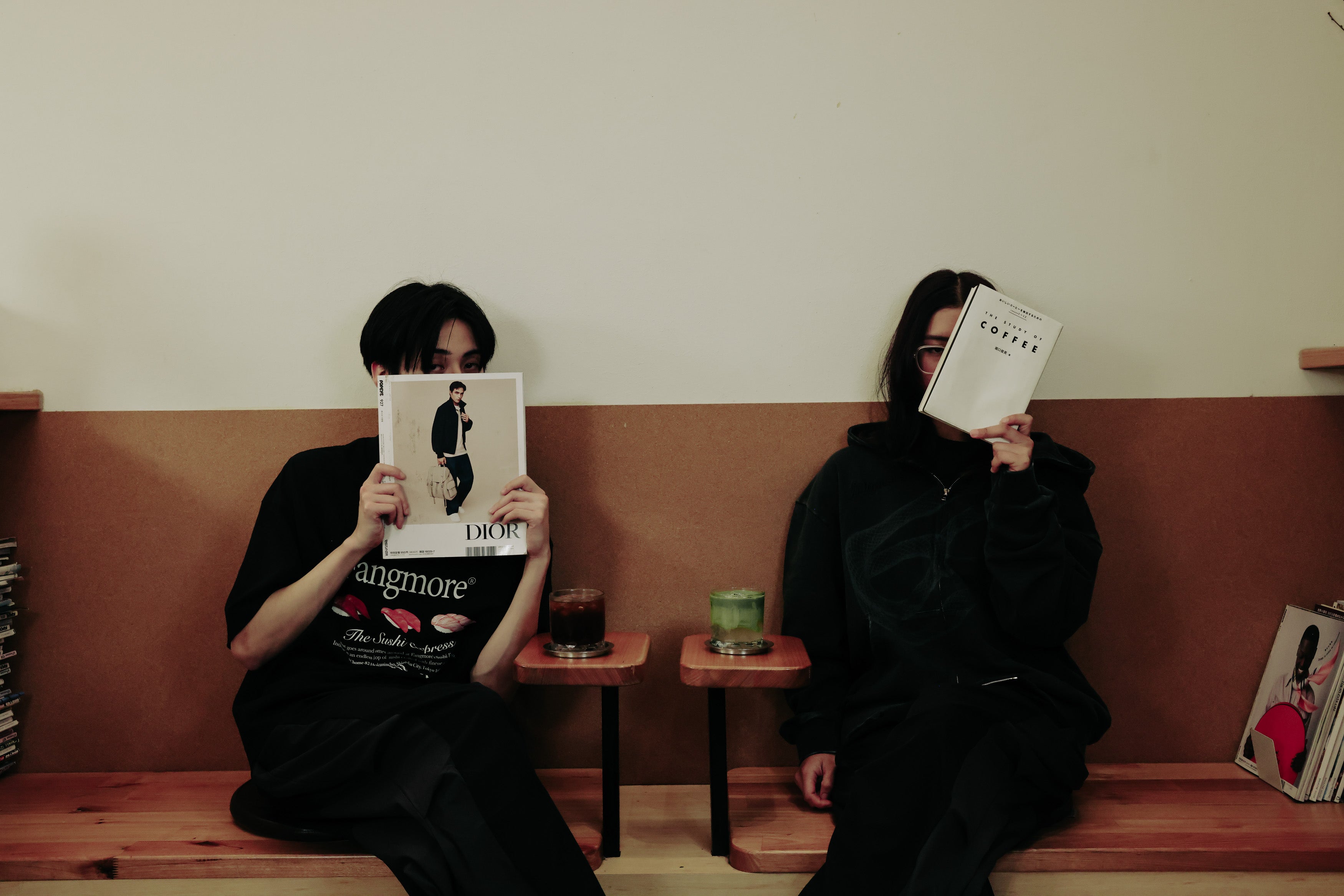 Two people sitting on a bench with books covering their faces.